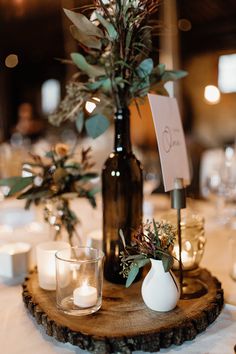 the table is set with candles, vases and greenery for an elegant centerpiece