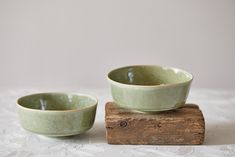 two green bowls sitting on top of a wooden block