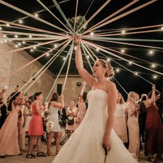 a woman in a wedding dress is holding her arms up as she walks down the aisle