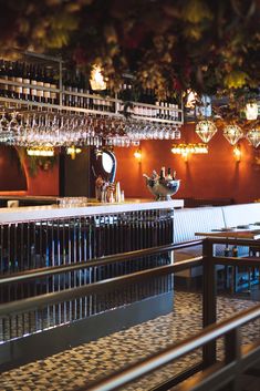 an empty bar with lots of wine glasses hanging from the ceiling and lights on the wall