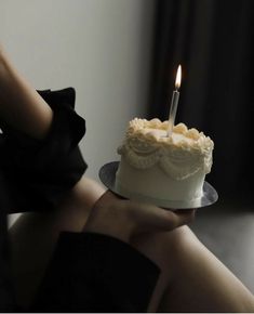 a woman holding a cake with a candle on it