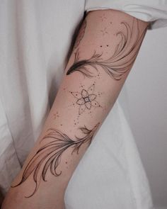 a person with a tattoo on their arm that has feathers and stars all over it