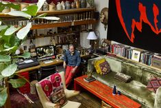 a man sitting on a couch in a living room next to a bookshelf