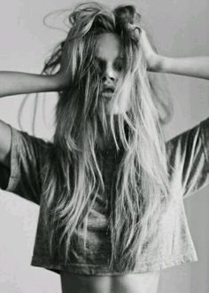 black and white photograph of a woman with her hair blowing in the wind while wearing a t - shirt