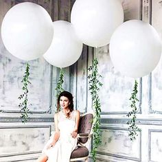 a woman sitting in a chair under some white balloons