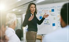 a woman standing in front of a whiteboard giving a presentation