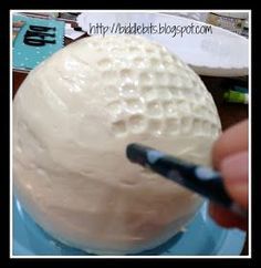 a person holding a pen in front of a white ball on a blue plate