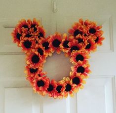 a mickey mouse wreath hanging on the front door with sunflowers attached to it