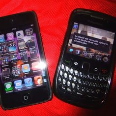 two cell phones sitting next to each other on a red blanket