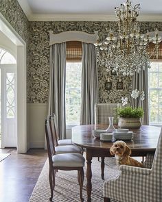 a dining room table with chairs and a dog sitting on the floor in front of it