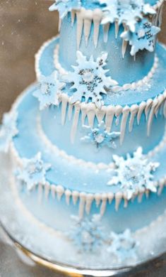 a three tiered blue cake with snowflakes on it