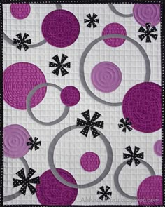 a quilted wall hanging with purple and black designs on it's sides,