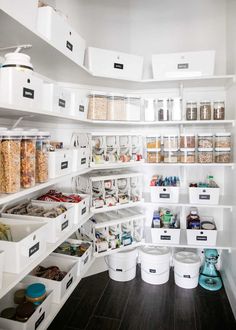 an organized pantry with white bins filled with food and containers full of cereal on the shelves