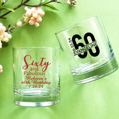 two personalized shot glasses sitting next to each other on a green surface with flowers