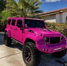 a bright pink jeep parked in front of a house with palm trees on the driveway