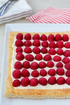 a cake with white frosting and raspberries on it sitting on a plate