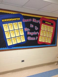 a bulletin board with question marks on it in a school hallway, next to a blue and yellow striped carpet