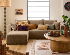 a living room with a couch, coffee table and potted plants in the corner