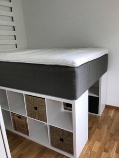 a bed with drawers underneath it and a mattress on the bottom shelf above them in a room