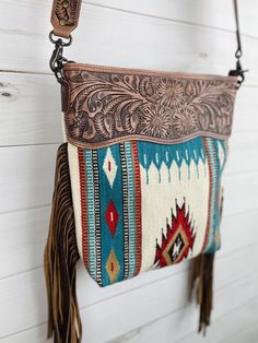 a purse hanging on the side of a white wall with a brown leather tassel