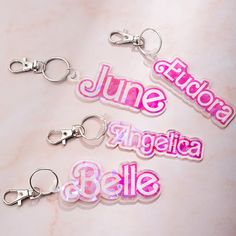 three keychains with the words june, july, and august written in pink