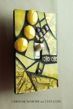 a light switch cover with yellow and black glass designs on it's side, hanging from the wall