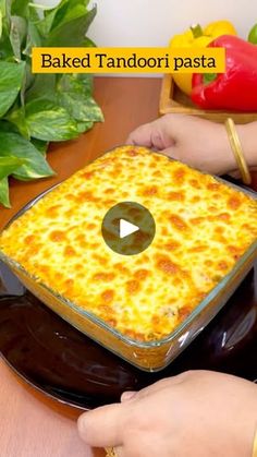 a person holding a plate with a casserole in it on top of a table