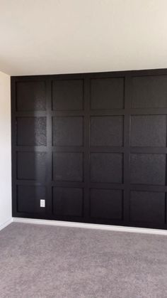 an empty room with black paneled doors and carpeting on the floor in front of it