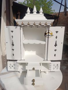 an open white cabinet sitting on top of a table