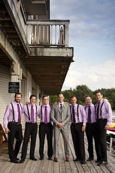 a group of men standing next to each other on top of a wooden floor near a building