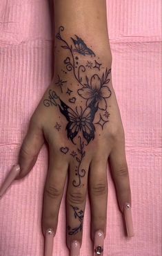 a woman's hand with a butterfly tattoo on it, and flowers in the middle