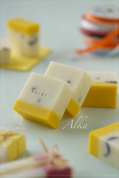 several pieces of yellow and white soap on a table next to other small objects with writing on them