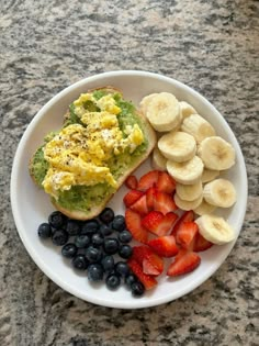 a white plate topped with fruit and an egg salad next to sliced banana's