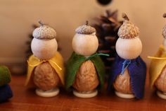 five small wooden figurines are lined up on a table next to a pine cone