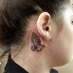 a woman with a small tattoo on her neck and behind her ear is a praying hand