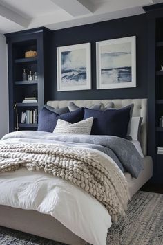 a bedroom with blue walls, white bedding and two framed pictures on the wall