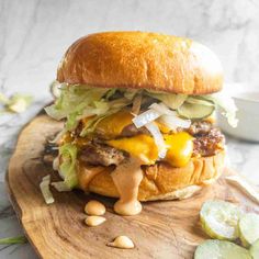 a cheeseburger with lettuce, onions and pickles on a cutting board