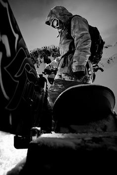 a man riding a snowboard down the side of a snow covered slope in black and white