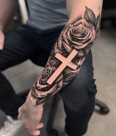 a man with a cross and roses tattoo on his arm