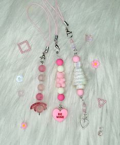 some pink and white items are laying on a fur covered surface with beads, chains, and charms