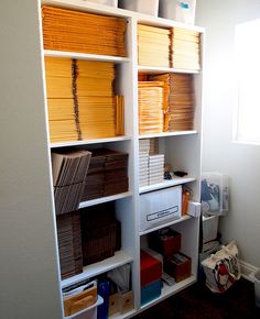 a white bookcase filled with lots of books and folders next to a window