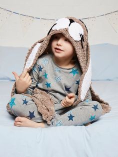 a little boy sitting on top of a bed wearing a bunny costume