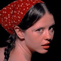 a woman with freckled hair wearing a red bandana