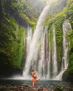 a woman standing in front of a waterfall