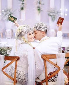 a man and woman sitting next to each other on a chair holding up their hands