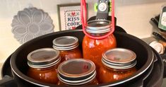 there are many jars in the pan on the stove top and one is filled with hot sauce