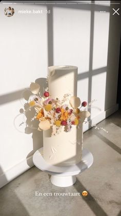 there is a white cake with flowers on the top and bottom tier, sitting in front of a window