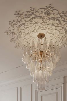 a chandelier hanging from the ceiling in a room with white walls and flooring