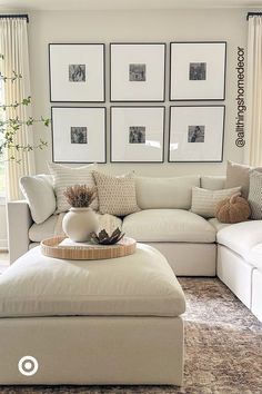 a living room filled with white furniture and pictures on the wall above it's coffee table