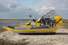 a yellow boat sitting on top of a sandy beach next to a body of water